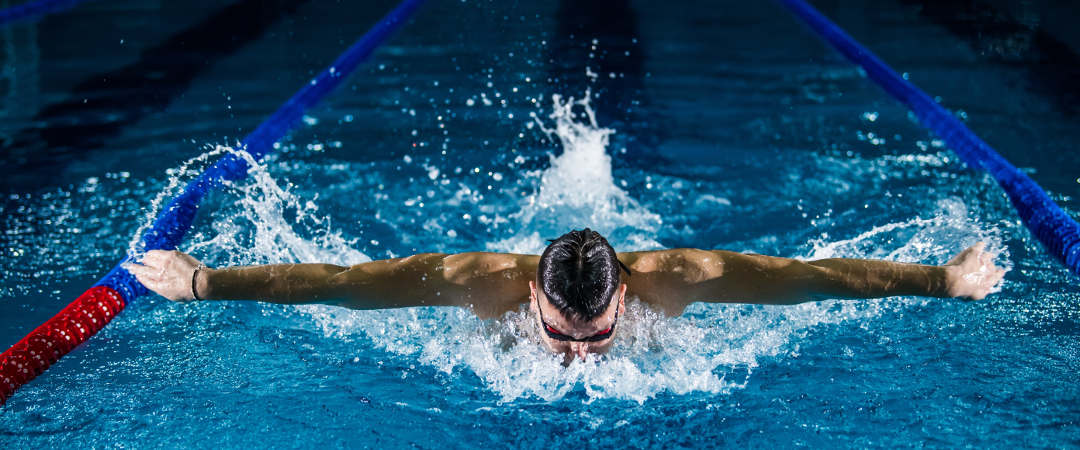 man swimming butterfly stroke in a lap pool