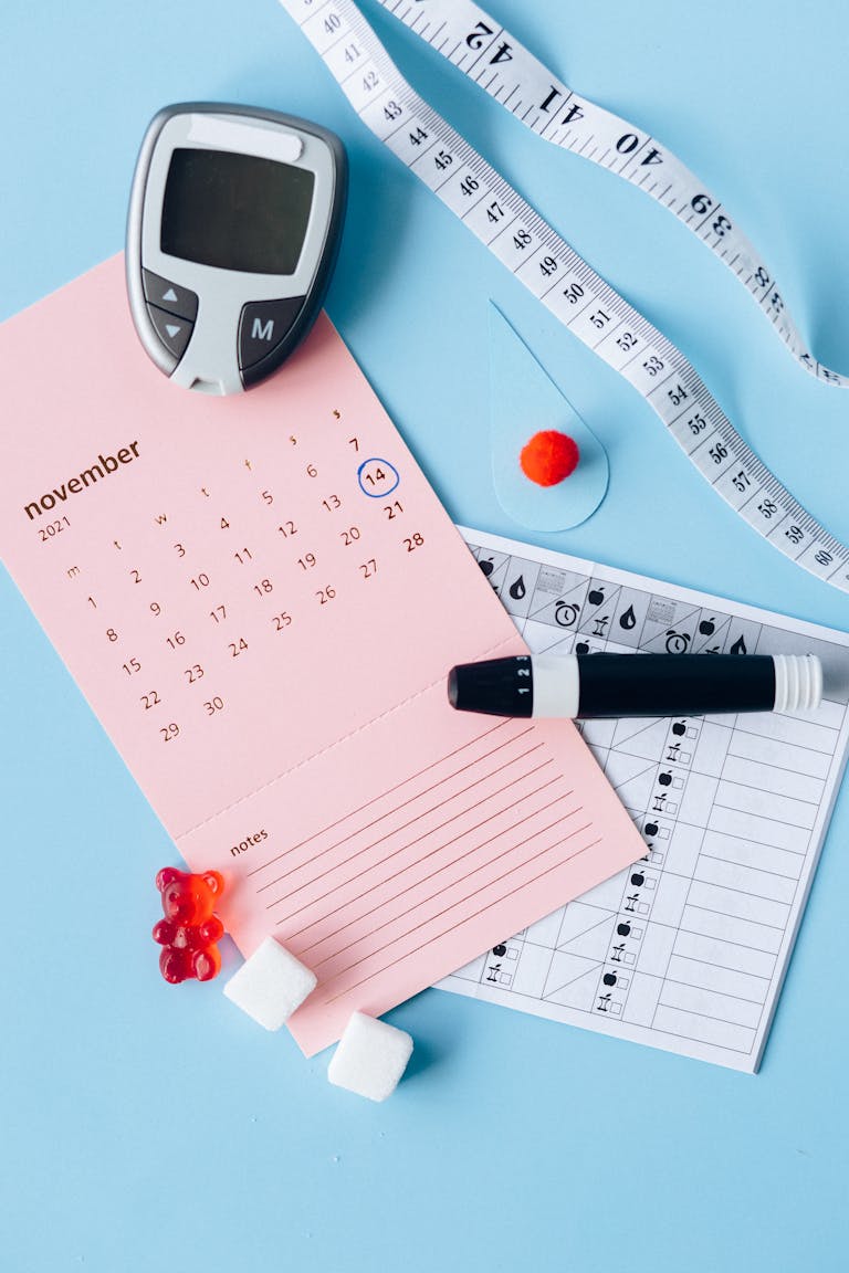 Flat lay of diabetes awareness tools on a blue backdrop with calendar.