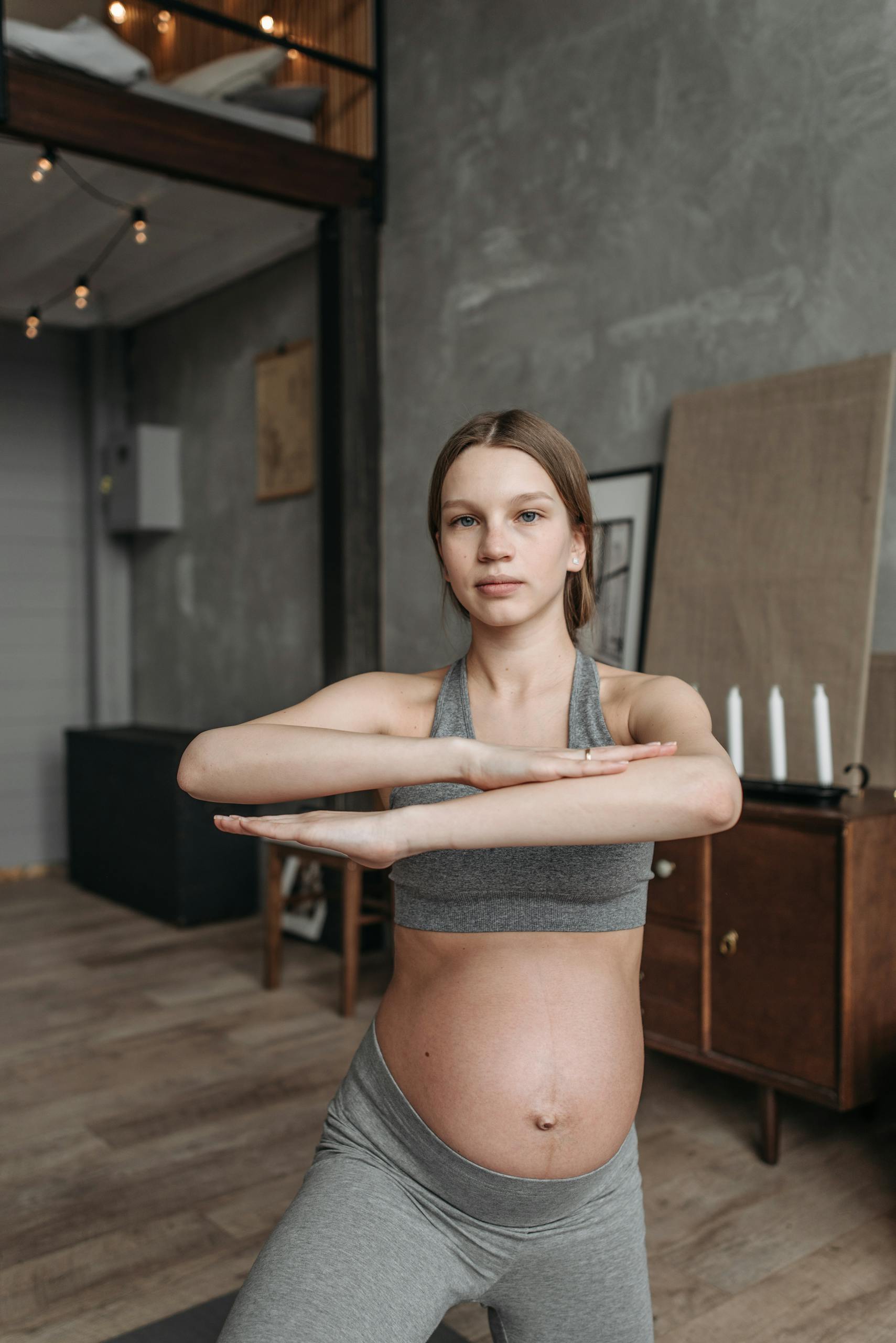 Pregnant woman in activewear doing yoga indoors promoting wellness and fitness.