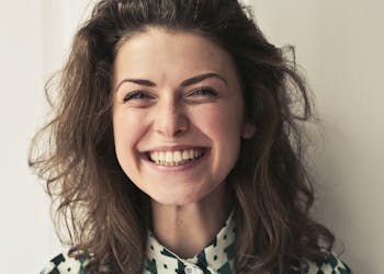 Portrait of a joyful brunette woman with a vibrant smile indoors, capturing happiness and positivity.