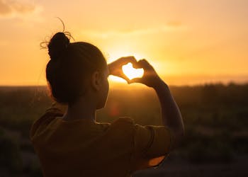 Silhouette of a person forming a heart with hands against a Morocco sunset.